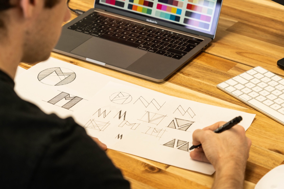 A graphic designer sketching logo ideas and brand concepts on paper: good branding is the moment when name, look, and meaning click into one thing