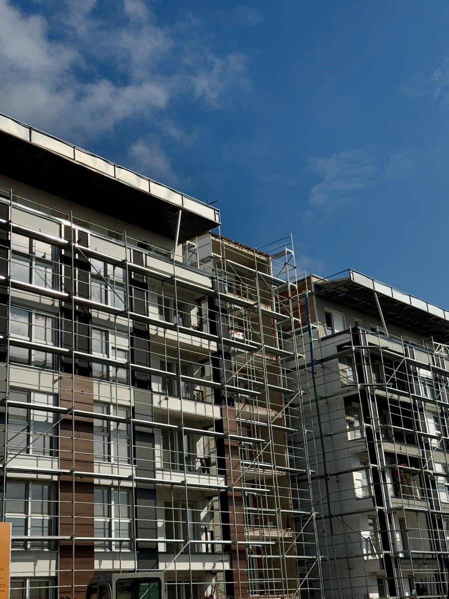 A building frame with scaffolding rising against a blue sky at a construction site: everything worth building looks messy in the middle, scaffolding comes down eventually, the structure underneath is what matters