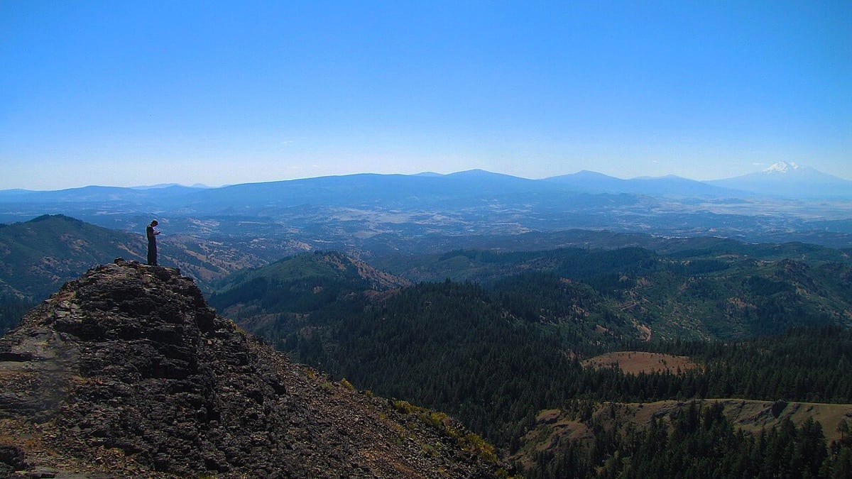 A climber committed mid-route on a sheer rock face: follow through as physical commitment