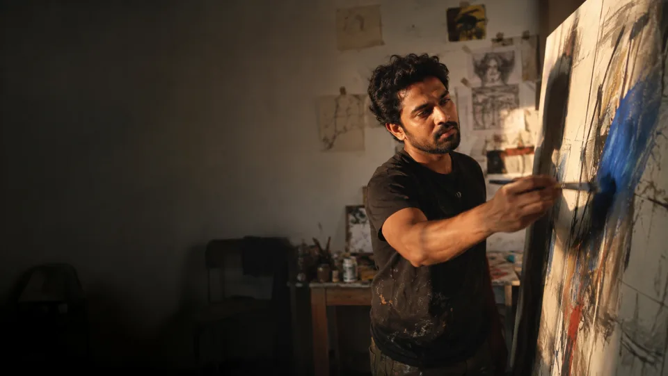 An artist adding colour to a canvas in a sunlit studio