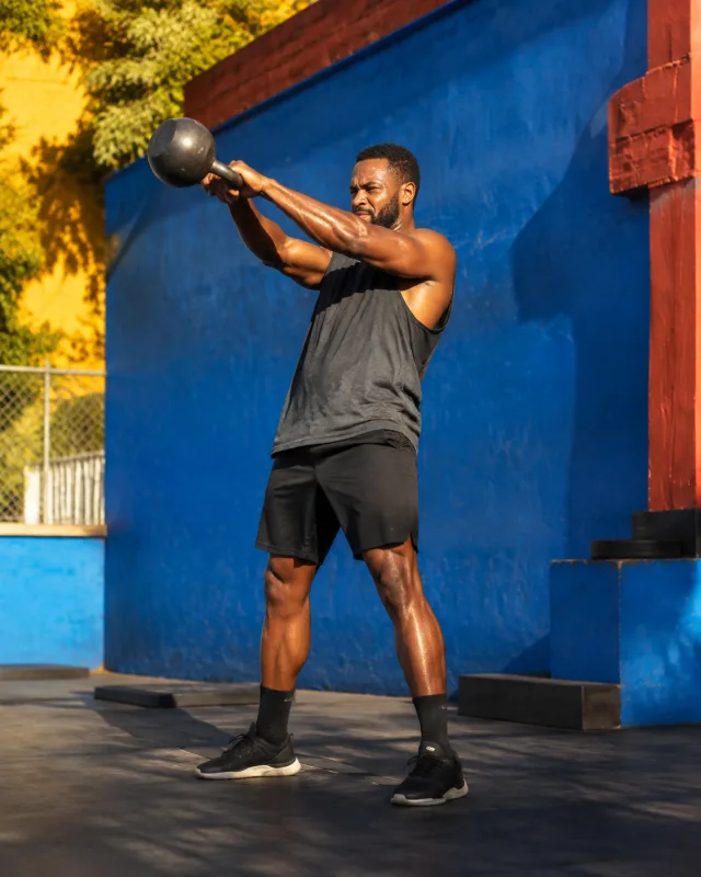 A man practising strength training outdoors beside a blue wall
