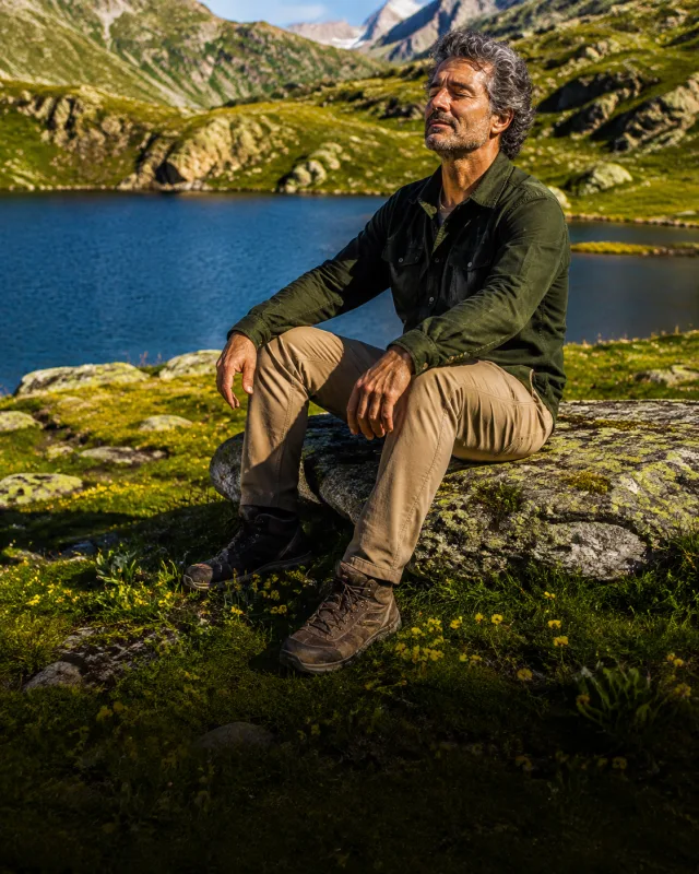 A man sitting quietly beside a lake in the mountains
