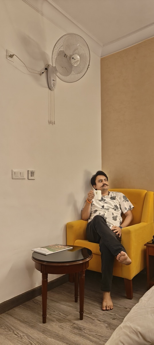 A man sitting alone in contemplation, holding a coffee cup on a yellow chair