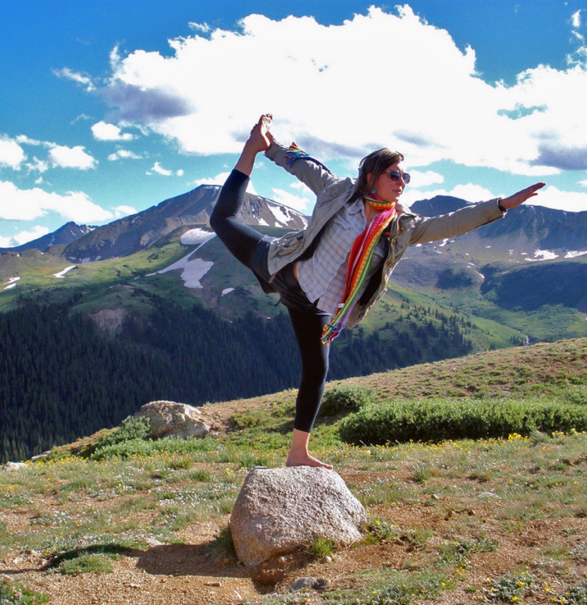 Person balancing in a yoga pose outdoors against a mountain backdrop