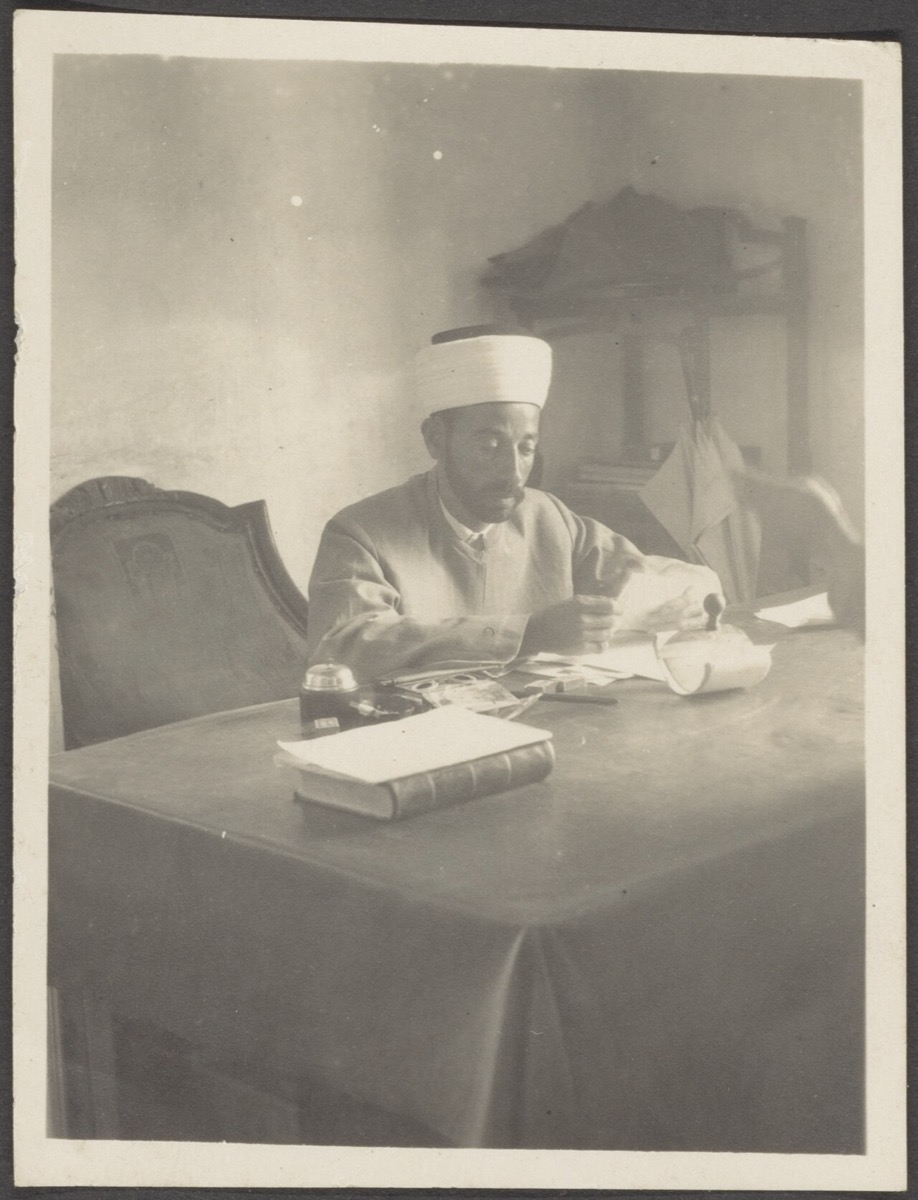 A man working alone at a desk, head down, focused on his work
