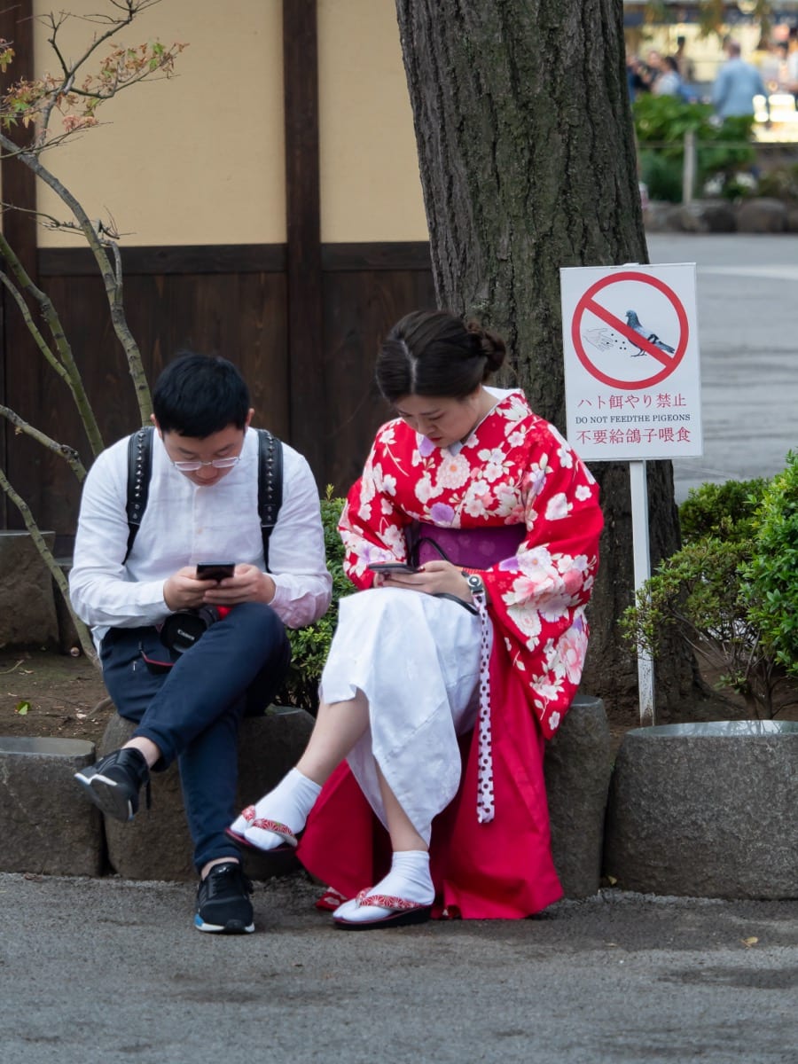 Two people sitting together but buried in their phones: shared space, stolen attention