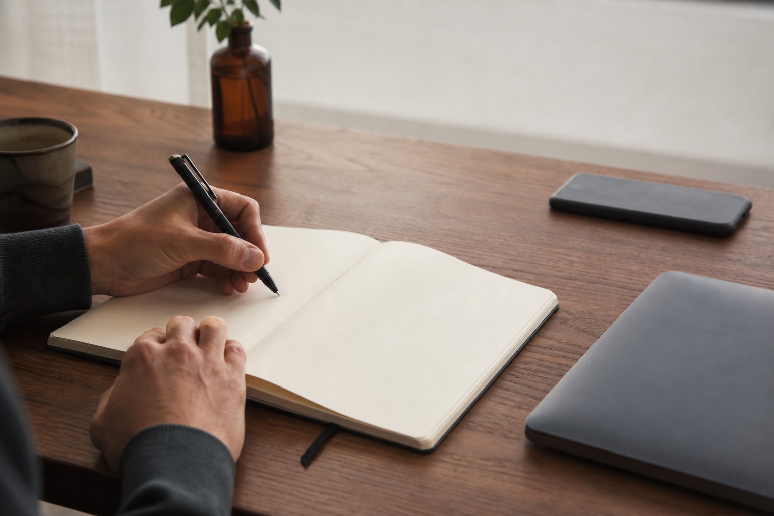An adult writing a single-task plan while the phone remains face-down and out of reach