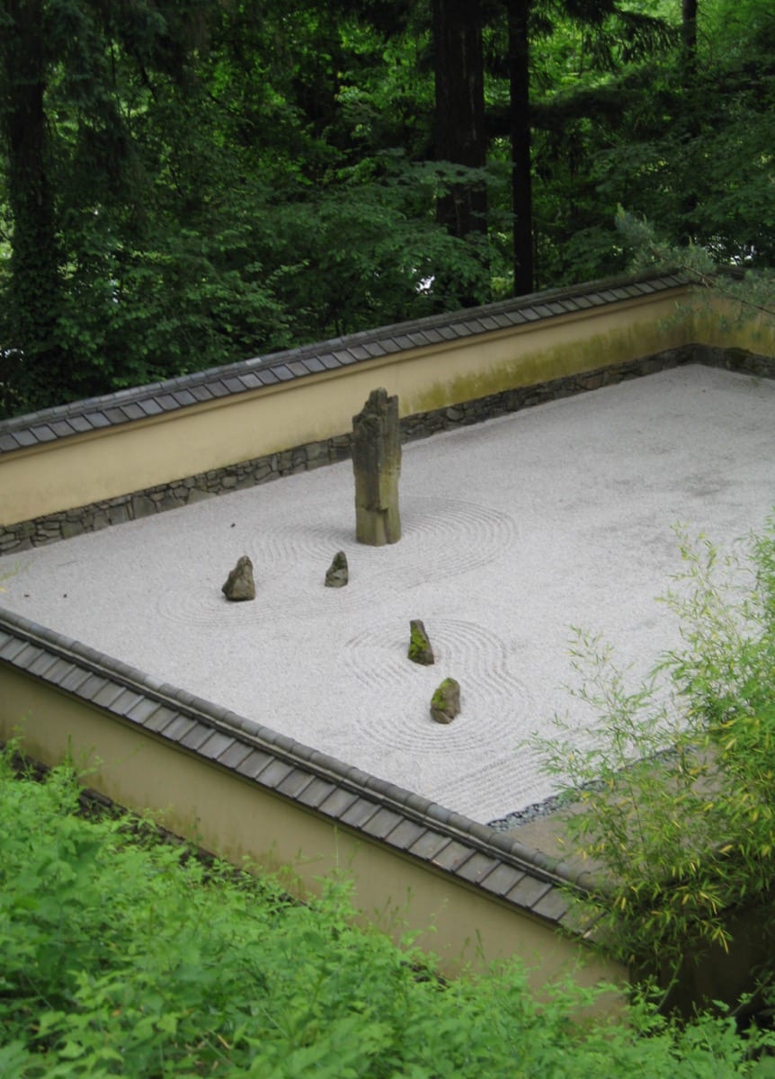 A still zen garden symbolising grounded calm: quiet confidence deepens under scrutiny because it is not a performance