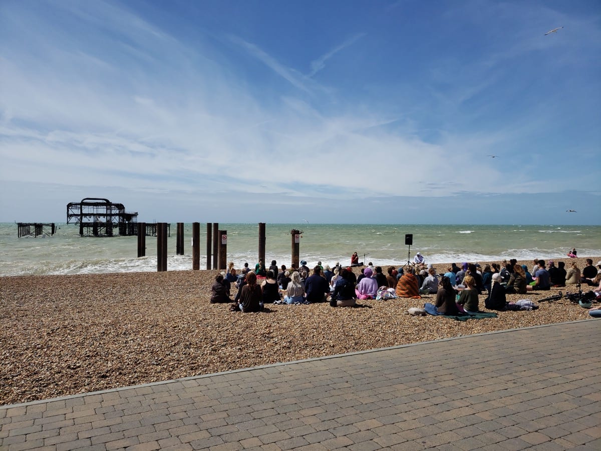 Person sitting in quiet meditation on a beach: the strength in weakness begins with the honesty to face what is actually there